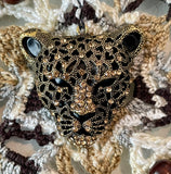 Close up of brass jaguar head with golden rhinestones.
