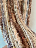 Close up of yarns in colors of brown, tan and cream.